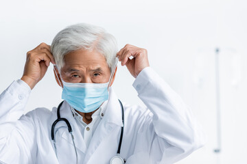 Senior asian doctor wearing medical mask in clinic