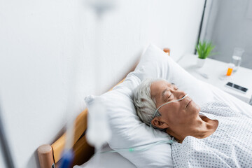 Fototapeta premium Asian patient with nasal cannula lying on bed in hospital ward