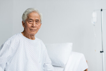 Senior asian patient looking at camera in hospital ward