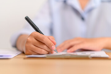 female employee holding a pen and writing on the document
