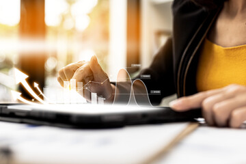 Businesswoman using a tablet to view company financial reports, graphics showing financial and numerical growth data. The concept of financial management to grow and be profitable.