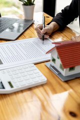 Fototapeta premium Real estate contract agreement concept. Buyer is signing house purchase contract with seller. Salesperson calculates house purchase cost and explains details on contract.