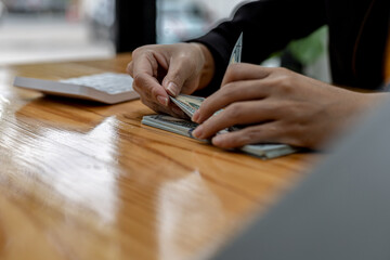 Woman counting dollar bills, she is a cashier serving customers in front of the cashier counter, she counts the money after the service is closed to verify the balance. Conceptual image of money.