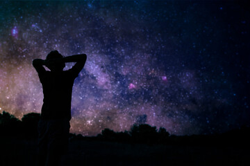 Fototapeta na wymiar Silhouette of a man enjoying countryside under the starry skies.