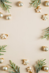 Fototapeta na wymiar Beige vertical Christmas background with golden balls, stars, fir branches. Christmas frame. Flat lay, top view, copy space. Nordic, hygge, cozy Christmas decor.