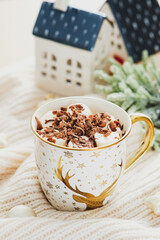 Cup of coffee with marshmallows and Christmas decorations on knitted plaid. Cozy home, hygge, bohemian style.