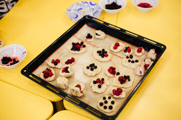 children make cookies with berries at a yellow table 