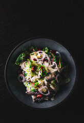 Mediterranean red beans salad with mix of lettuce leaves and onion on black plate