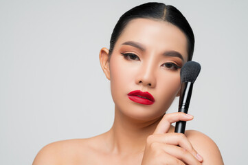 Portrait of Beautiful Asian woman holding makeup blusher brush