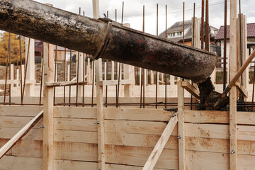 Filling concrete from mixer into wooden formwork of the foundation.Concrete works, cementing