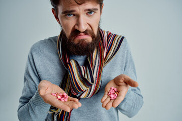 sick man in a sweater with pills in hand health problems light background