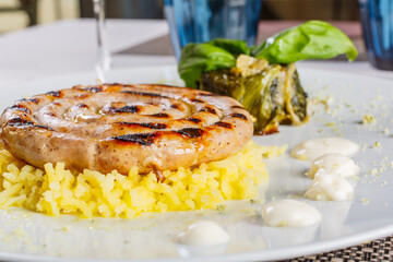 Salsiccia arrotolata su patate schiacciate con contorno di scarole servita in un ristorante