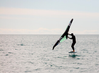 sportsman with wingfoil sailing, in the sea