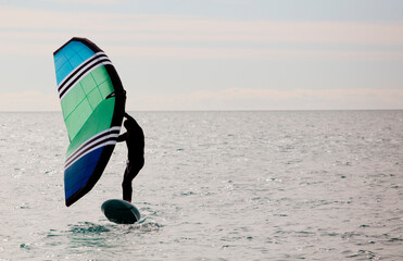 sportsman with wingfoil sailing, in the sea