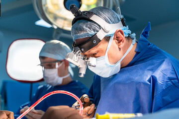 Spinal surgery. Group of surgeons in operating room with surgery equipment. Doctor looking at the...