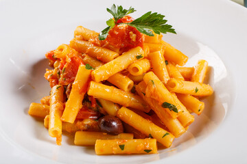 Piatto di pasta con baccalà, pomodori, olive e prezzemolo servito come primo piatto in un ristorante