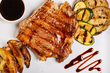 Bistecca di carne con salsa barbecue, patate al forno e verdure grigliate fotografata dall'alto