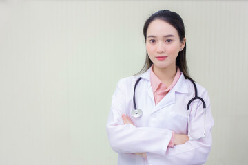 Young beautiful Asian woman doctor Standing with arms crossed happy and smile in hospital. Wearing a white robe and stethoscope