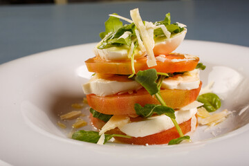 Piatto da ristorante con pomodori freschi, mozzarella di bufala, formaggio grattugiato e rucola