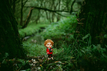 A toy boy walks through the old forest