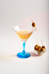 Still-life. Beautiful martini glass and light olives on a light background