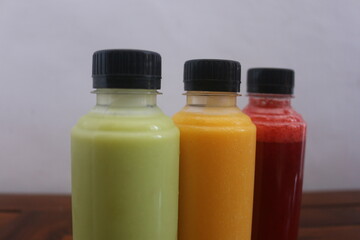 Avocado, mango, strawberry juice served in plastic bottles with black lids

