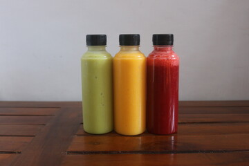 Avocado, mango, strawberry juice served in plastic bottles with black lids

