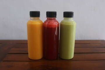 Avocado, mango, strawberry juice served in plastic bottles with black lids

