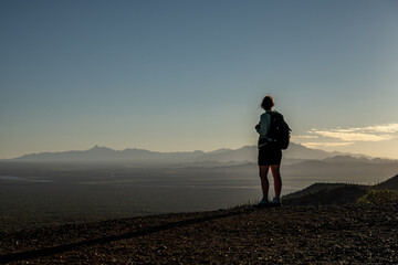 Female Hiker Stands At Cliff Edge Looking Over Saguaro National Park