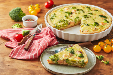 Homemade quiche with red fish, salmon, broccoli and cheese on wooden background