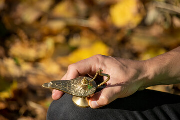 A man holds a gilded magic lamp of Aladdin