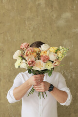 Beautiful bouquet of mixed flowers in mans hands. The work of the florist at a flower shop. Beautiful fresh bouquet. Flowers delivery.