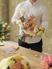 Flower shop. Beautiful bouquet of mixed flowers in bright color in man's hands. Work of the florist at a flower shop. Fresh cut flower.