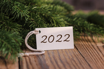 New Year 2022. Fir branches and a tag with the text 2022. New years card