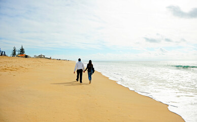 Couple walking on the beach of Faro in winter, Praia de Faro no inverno, Algarve Portugal Southern...