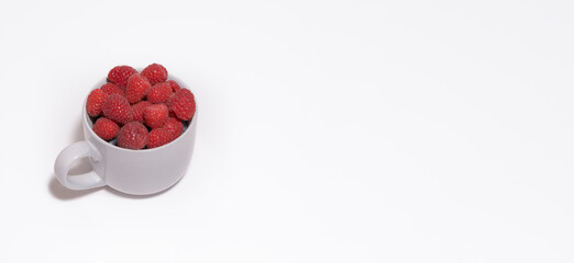 Raspberry berries in a large gray mug on a white background. Card