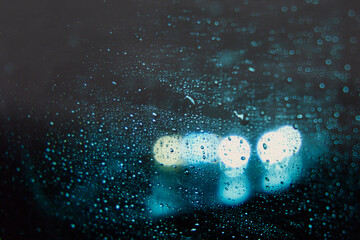 Abstract shot of raindrops on windshield at night during a rainstorm