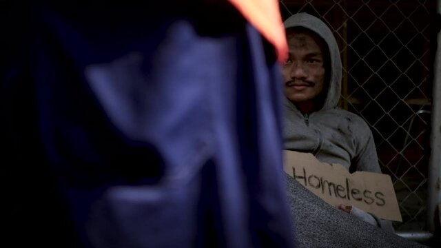 Homeless man with dirty clothes holding a cup and getting some money from kind peoples. 4K	