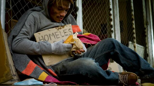 Homeless man with dirty clothes getting bread from kind people and eating with gluttonous, hunger. 4K