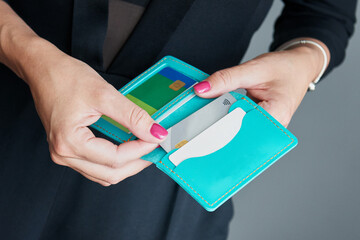 A woman in a business suit pulls out a credit card from her wallet.