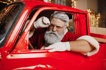 Santa Claus is preparing for Christmas. Portrait of Santa Claus driving. Stylish driver, new year,...