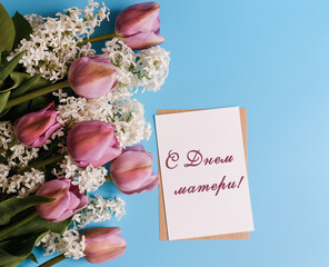 Postcard with the text in Russian Happy Mother's Day and a bouquet of beautiful flowers on a blue...