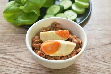 spicy chop pork Thai chili pasted topping salty egg eat couple with cucumber and fresh vegetable on plate