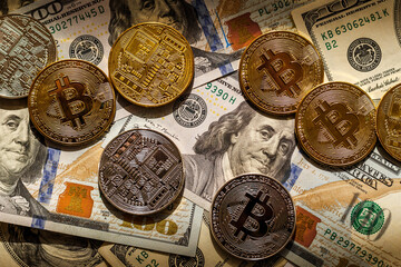 Golden Bitcoin lies on the banknotes.New virtual money. Crypto currency top view. Real coins of bitcoin on banknotes of one hundred dollars. Exchange, commercial. online business concept.