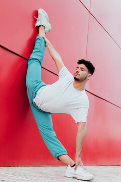 Male dancer practicing arabesque position while leaning on wall