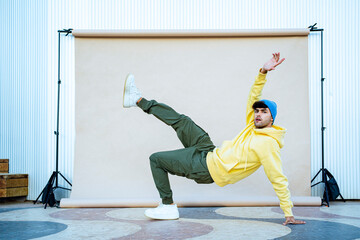 Young male dancer dancing on floor by backdrop