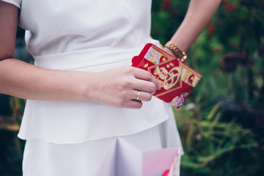 Woman's Hand Holding An Opened Red Envelope Or Red Packet Called Ang Pao Or Ang Pow, Also Hongbao Or Hungbao In Mandarin And Lai See In Cantonese. Selective Focus. 