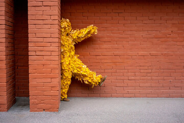 Woman in leaf costume walking by brick wall