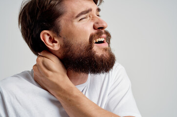 Obraz premium emotional man in a white t-shirt stress medicine pain in the neck light background