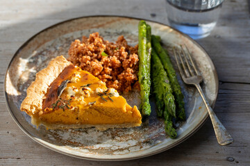 Pumpkin tart with feta cheese and herbs, asparagus and couscous
